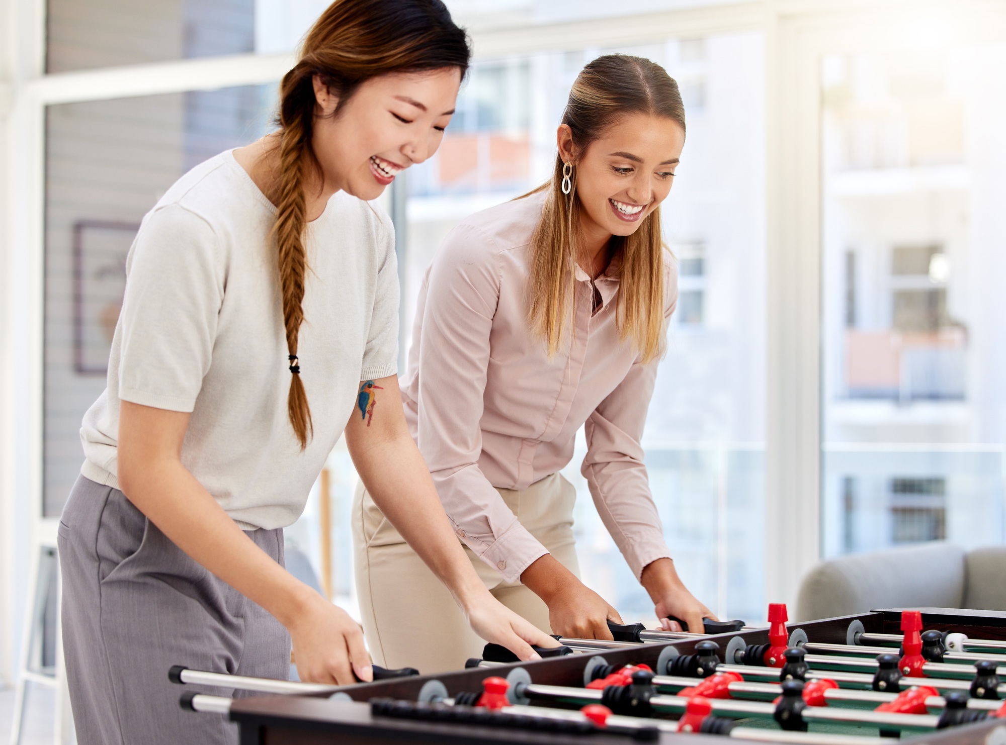 Happy employee playing table soccer, laughing and having office fun at their corporate job. Diverse